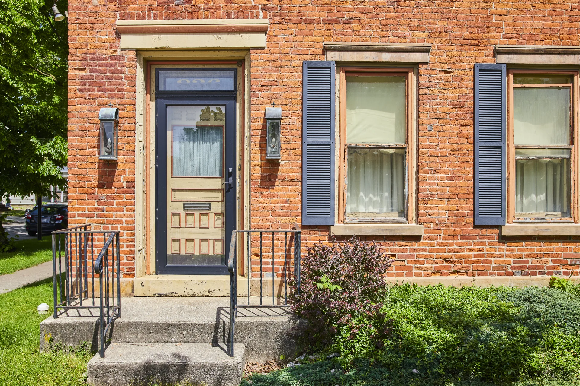 Brick home entry with black shutters, trim, and restored masonry detail
